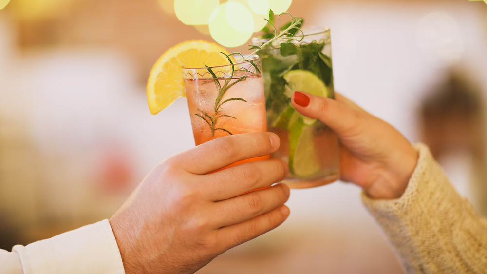 two hands toasting with cocktails