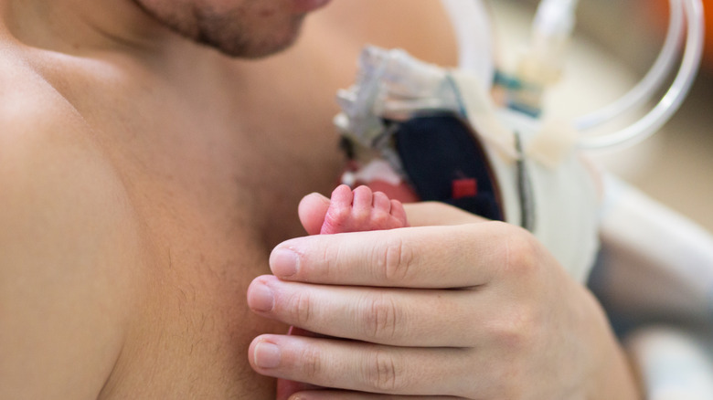 Father holding baby skin to skin