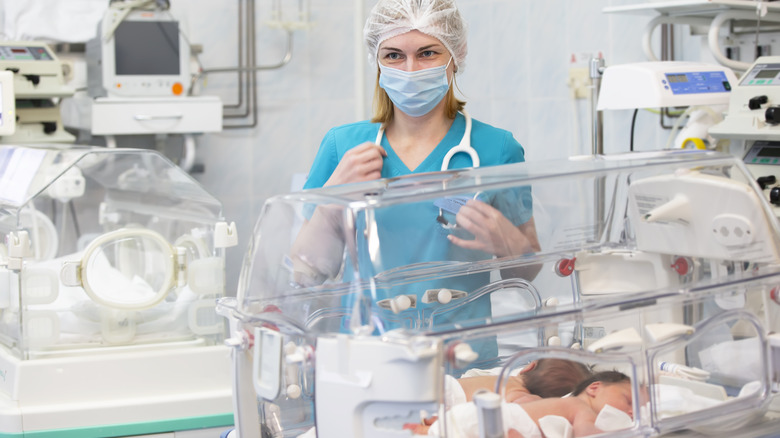 Doctor standing next to a baby in an incubator