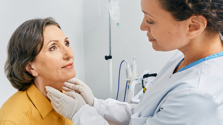 female doctor examining an older woman's thyroid gland 