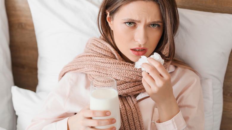 Sick woman in bed drinking milk