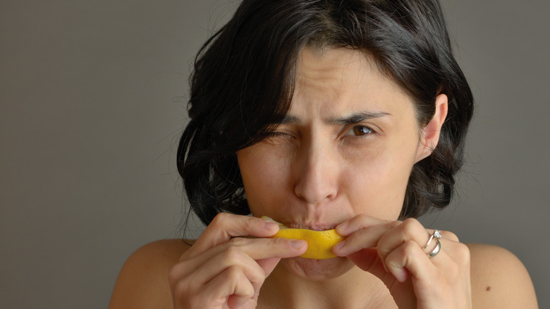 woman eating lemon peel grimacing