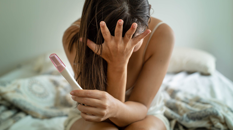Frustrated woman holding pregnancy test