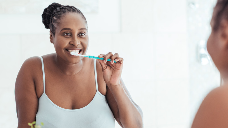 Smiling woman brushing teeth