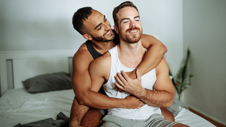 two men embracing in bed