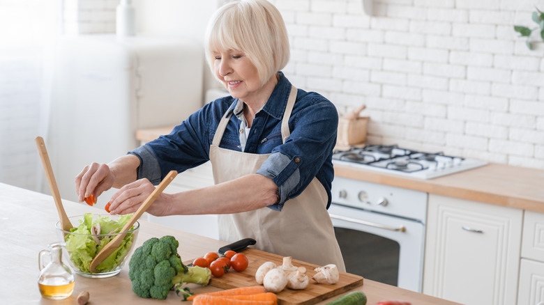 woman adding tomatoes to salad