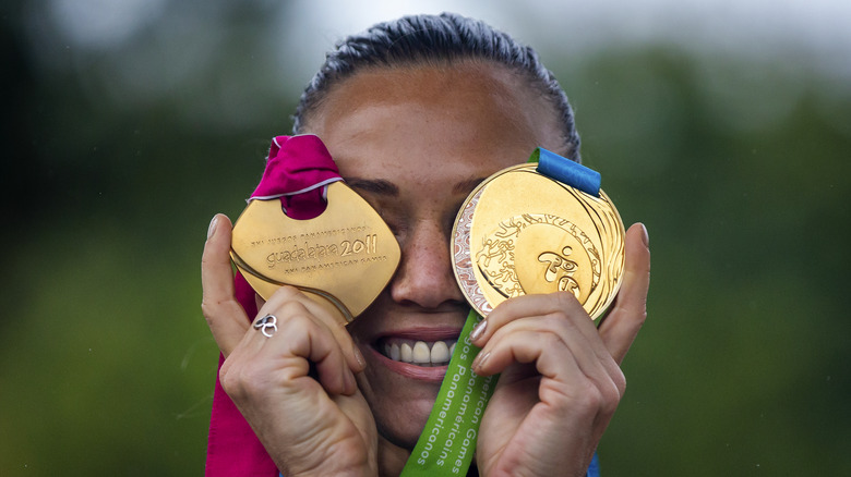 woman with 2 gold medals covering her eyes