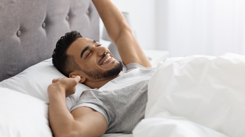 smiling man waking up in bed