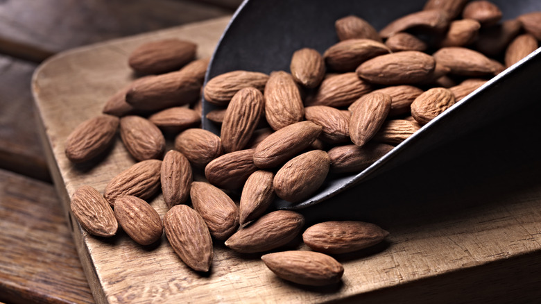 scoop of almonds on a wood cutting board