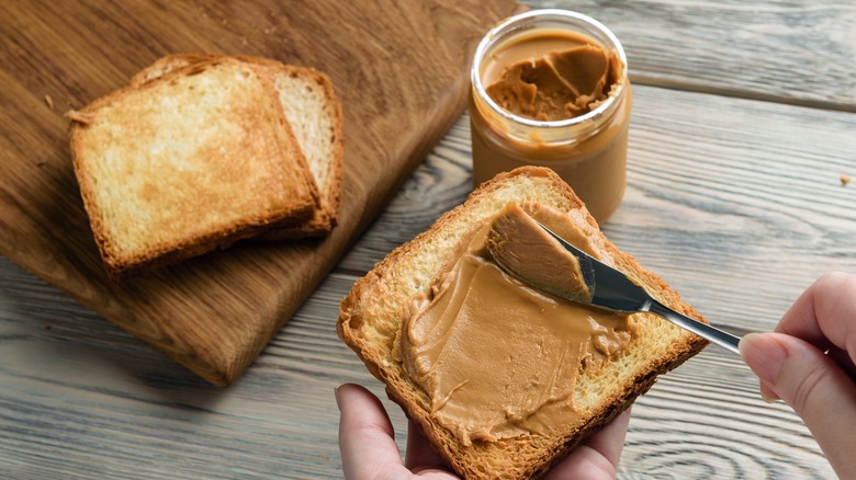 female hands spreading peanut butter on toast