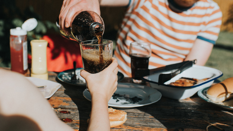 person pouring a soda at a picnic