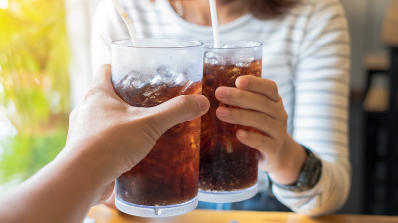 Friends clinking two glasses of soda together