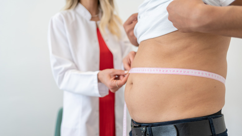 Man at doctor's office having waist measured