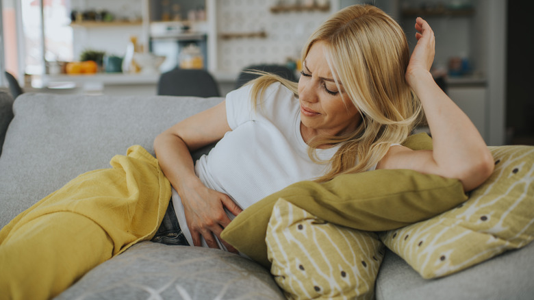 Woman on couch with stomach pains