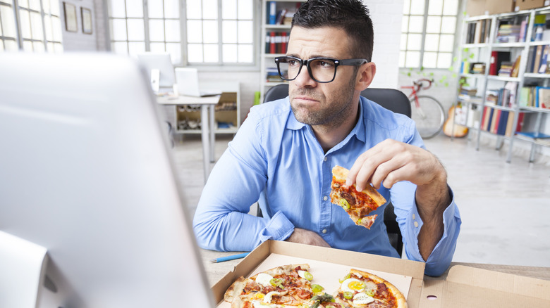 Man eating pizza and looking moody