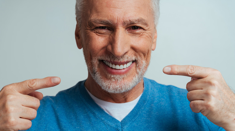 smiling man pointing at his teeth