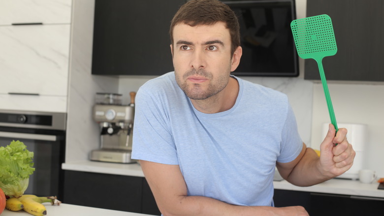 man trying to swat a fly in his kitchen