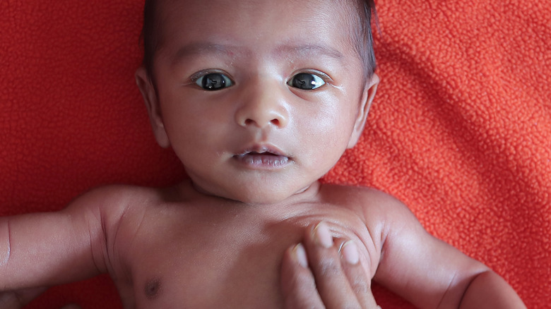 hand touching malnourished baby 