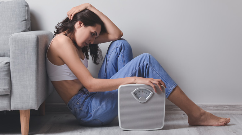 woman sitting on floor suffering anorexia