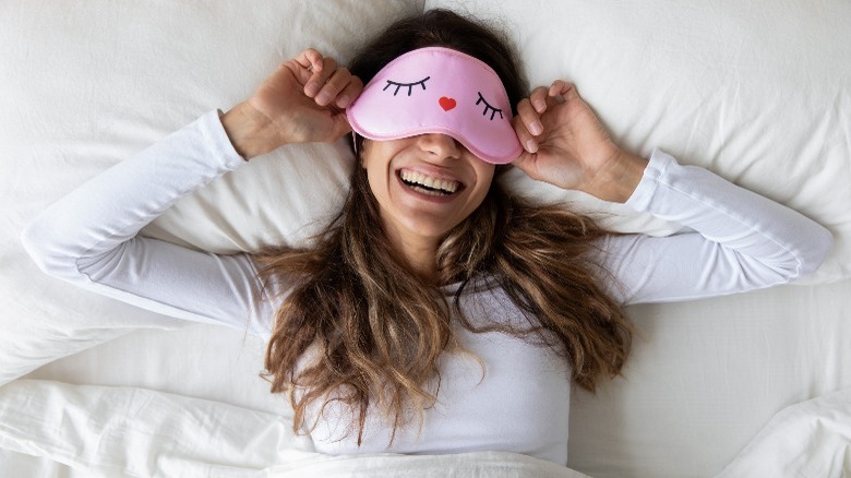 cheerful woman in bed wearing eyemask
