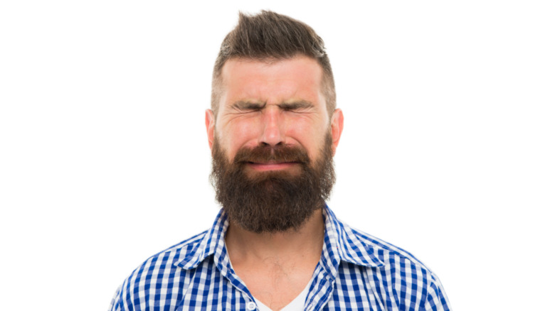 young man with a beard crying on isolated white background