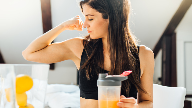 Woman making smoothie and flexing