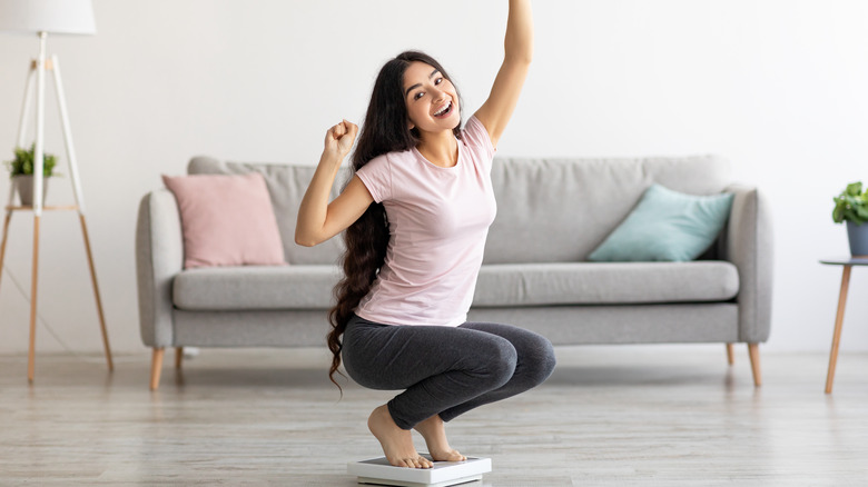 woman celebrating on the scale indicating weight loss