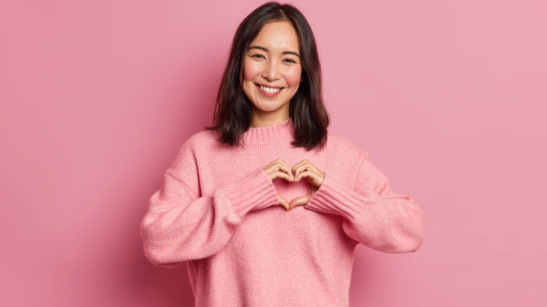 a girl with her hands over her chest in a heart formation smiling