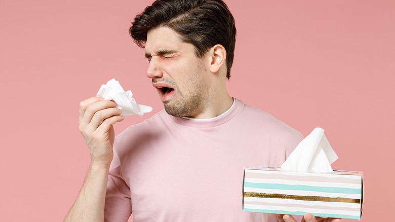 a man holding a box of tissues looking sick from weakened immune system