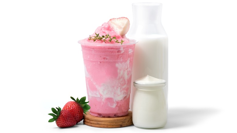 Strawberry yogurt smoothie next to milk and yogurt containers