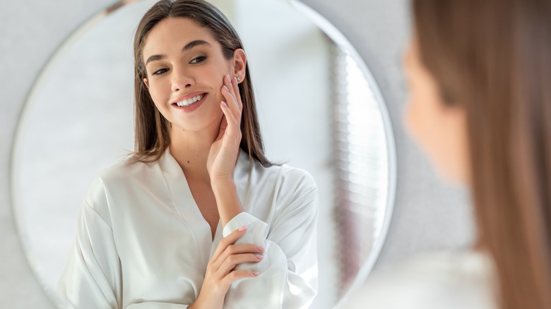 Woman admiring healthy skin through a mirror