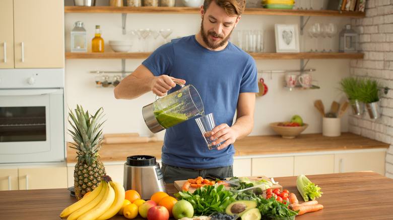 Man pouring fruits and vegetable smoothie into a glass