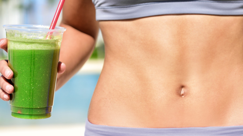 woman holding celery juice showing abs 