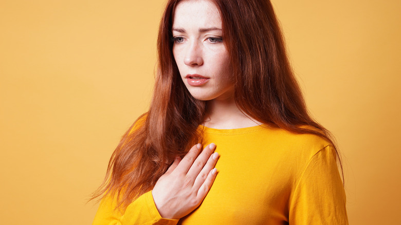 woman holding chest in pain