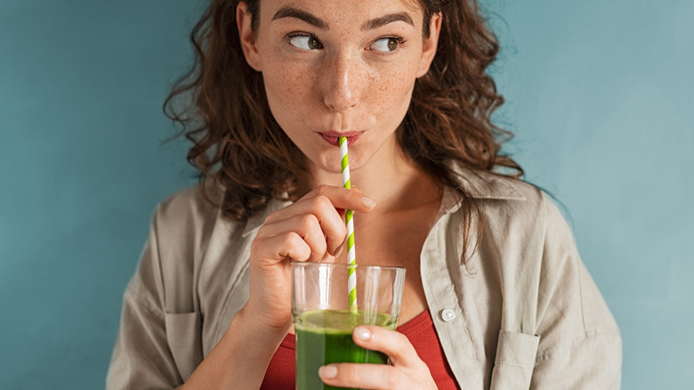 woman holding glass of green juice