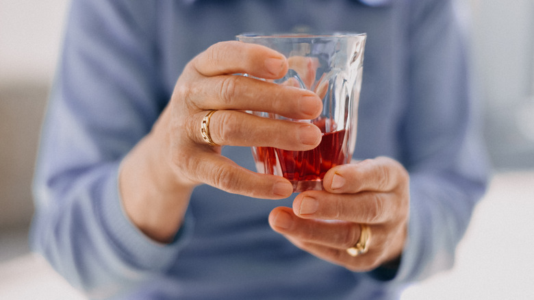 A woman's hands holding a glass of cranberry juice