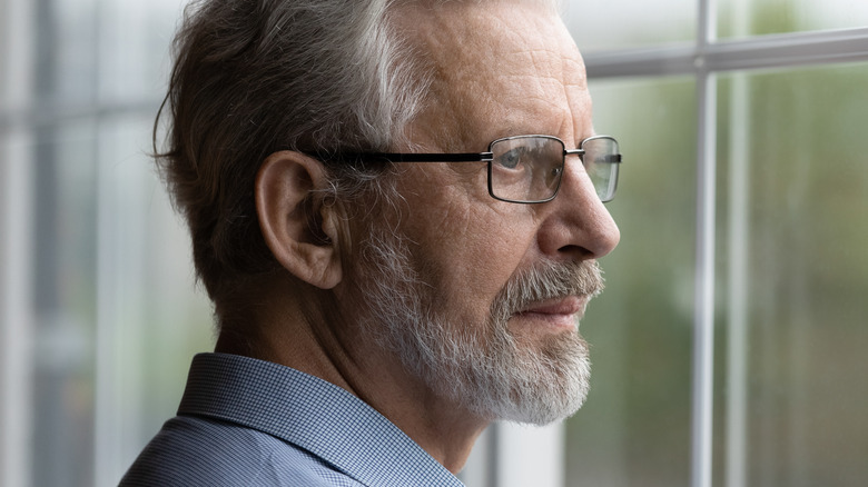 gray haired man staring out window