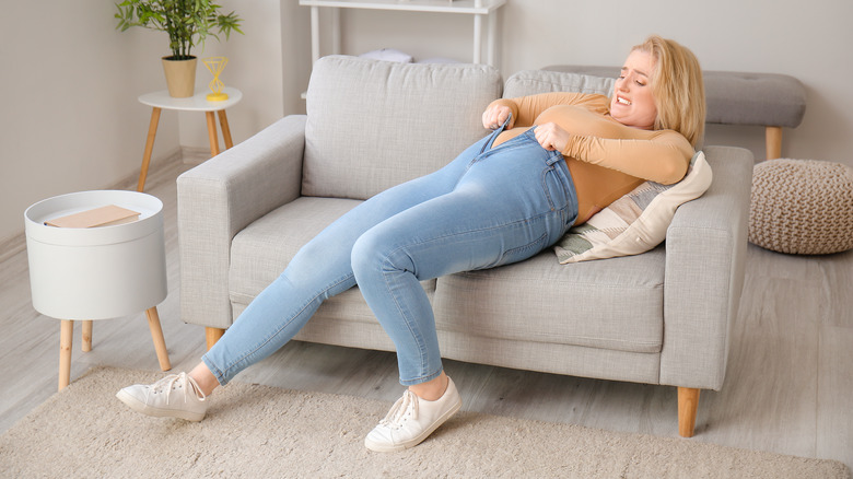 Reclining woman trying to zip up jeans