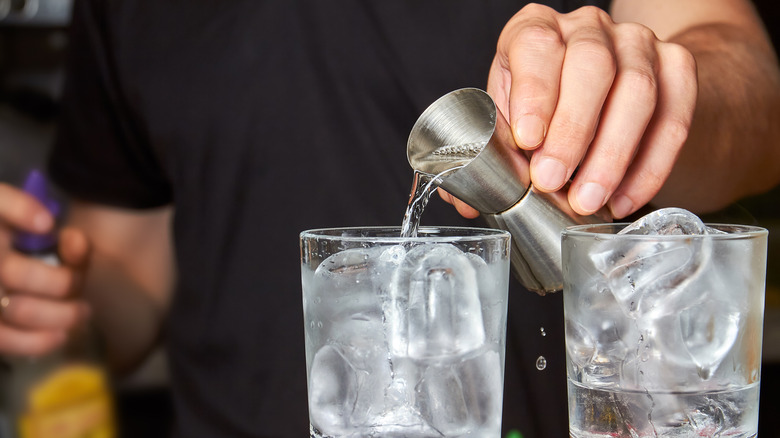 bartender pouring gin in glasses