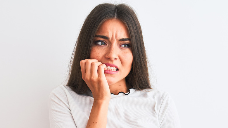 a young woman looking anxious biting her nails