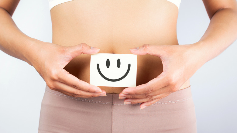 woman holding smiley face over stomach good digestion