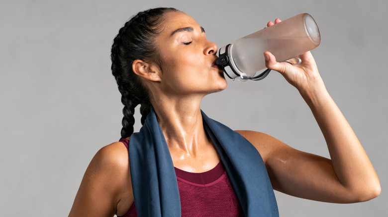 woman drinking water after workout