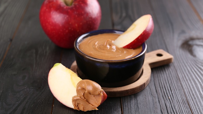 a cup of peanut butter with sliced apple