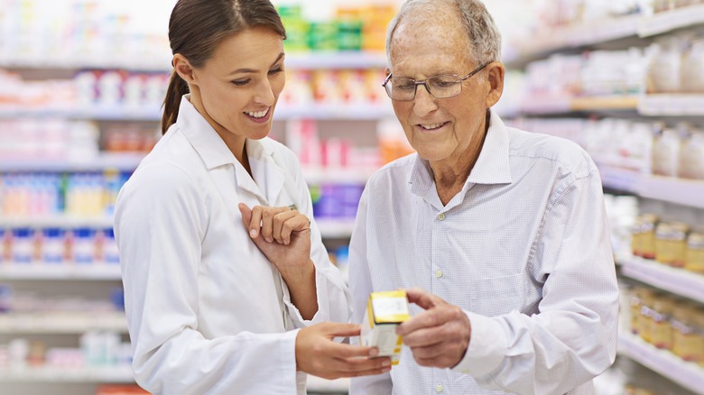 older man inspecting medication with pharmacist