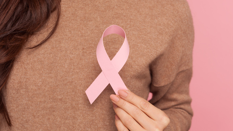 woman holding pink ribbon signifying breast cancer 