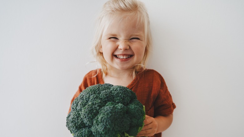 smiling little girl with broccoli