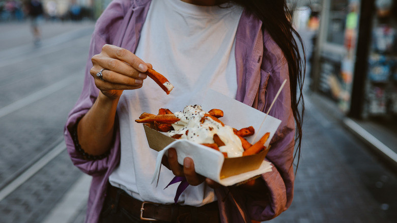 woman holding container of french fries