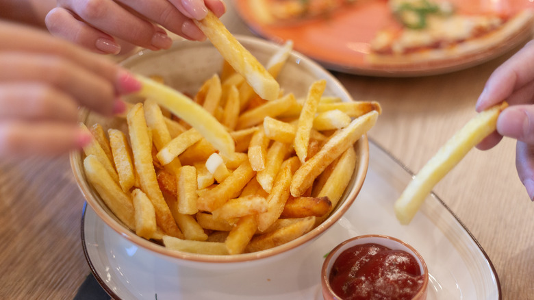 hands of women sharing fries