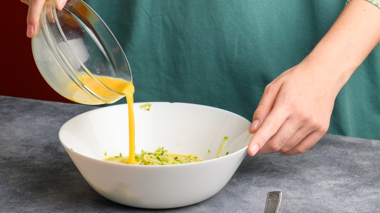 man pouring bowl of mixed raw eggs