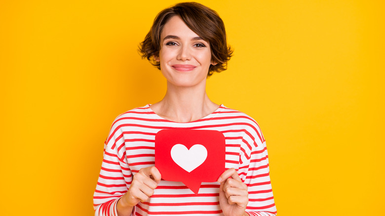 woman holding heart against orange backgroud